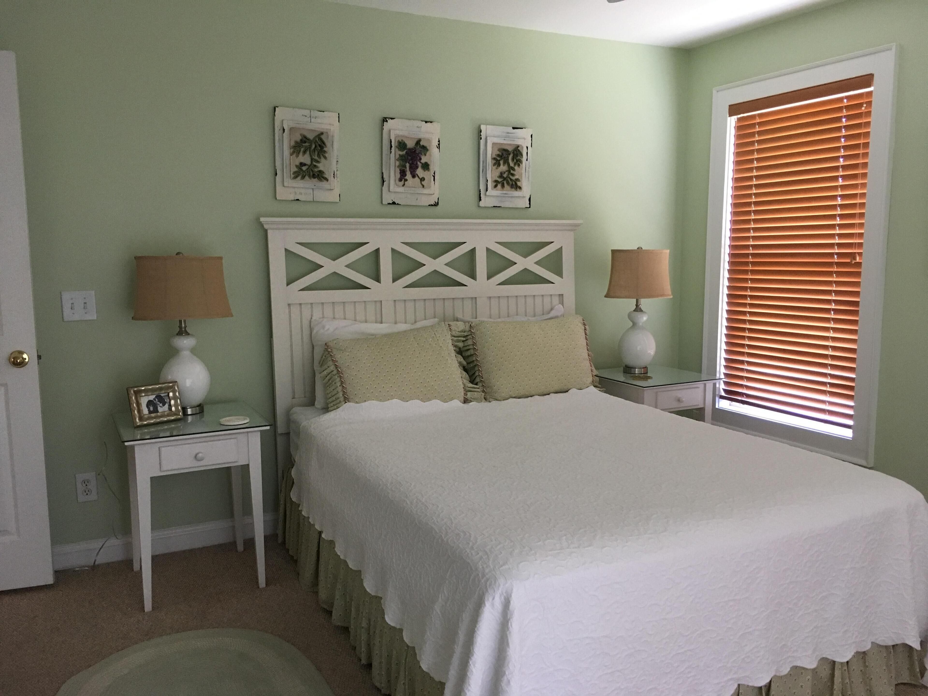 A bedroom with a bed, nightstands, a dresser, and a window with blinds.