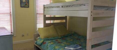 A bunk bed with a floral bedspread, two pillows, and a small shelf on top.
