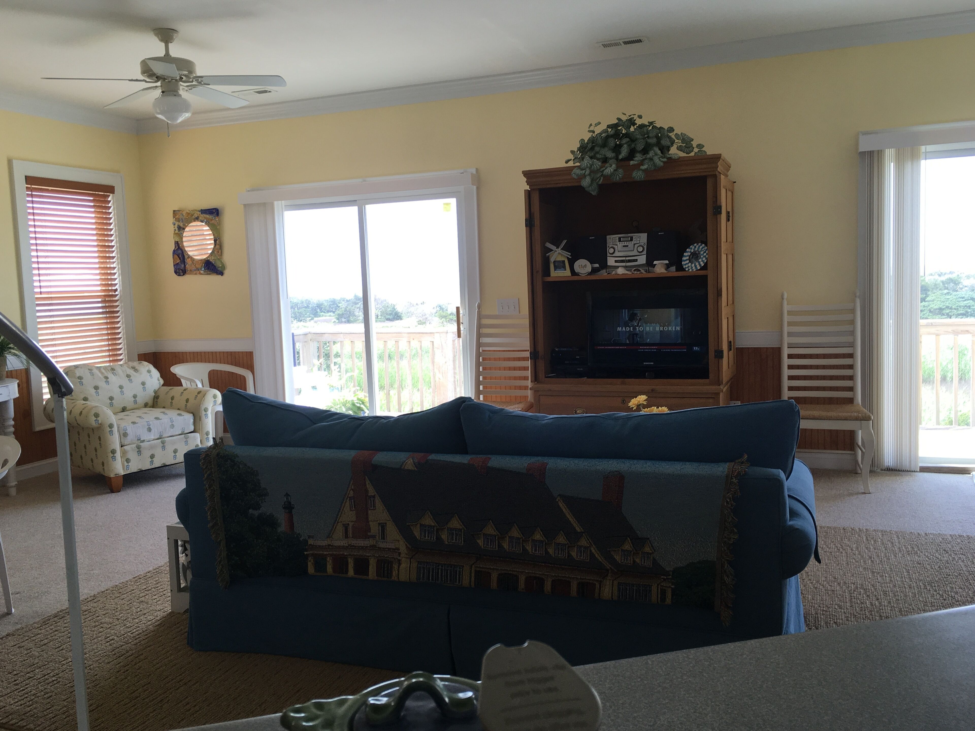 Ein Wohnzimmer mit einem blauen Sofa, einer Holz-Unterhaltungsecke und Blick auf ein Haus durch eine Schiebetür.