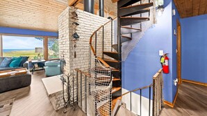 Un interior moderno con una escalera en espiral, una chimenea y vistas al exterior.