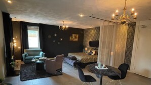 A modern living room with a sofa, chairs, a dining table, and a bed. - Gasterij Hotel Dennenoord (Boxtel)