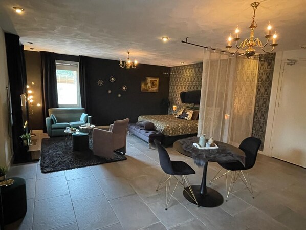 A modern living room with a sofa, chairs, a dining table, and a bed. - Gasterij Hotel Dennenoord (Boxtel)