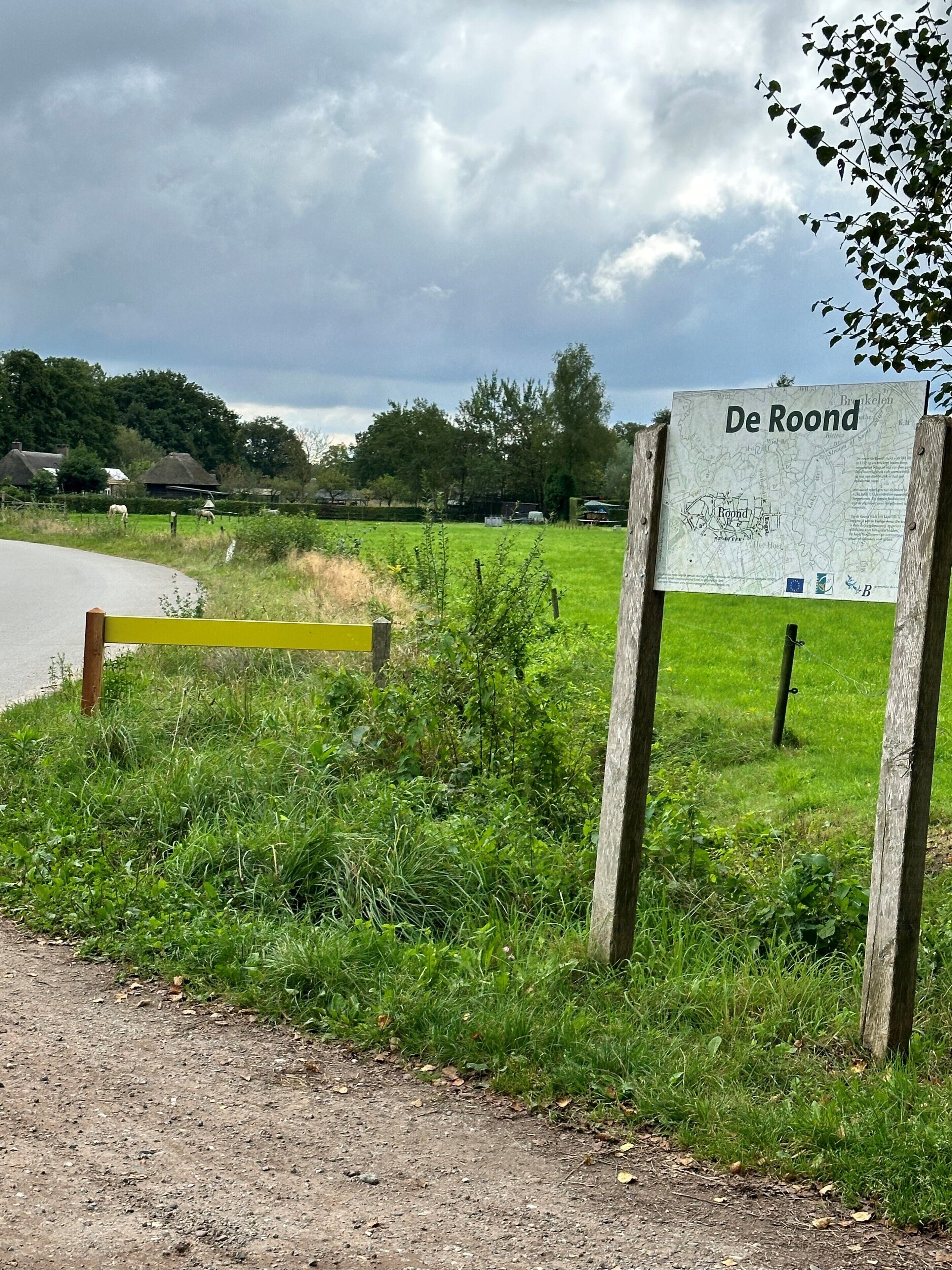 Un camino rural con un cartel que dice "De Roond" y un mapa.