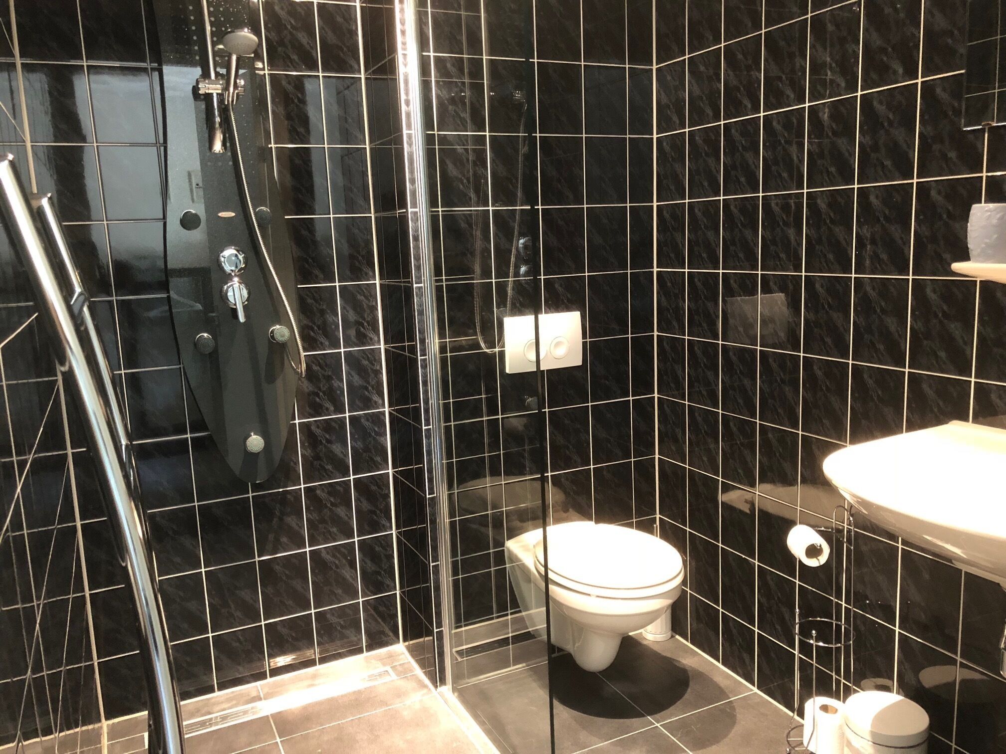 Une salle de bain avec une douche à parois de verre, des toilettes et un lavabo.