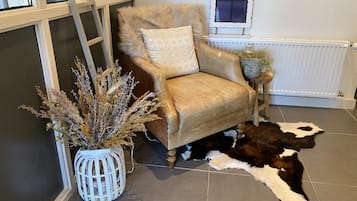 Een kamer met een leren fauteuil, een decoratieve plant en een koeienhuidkleed.