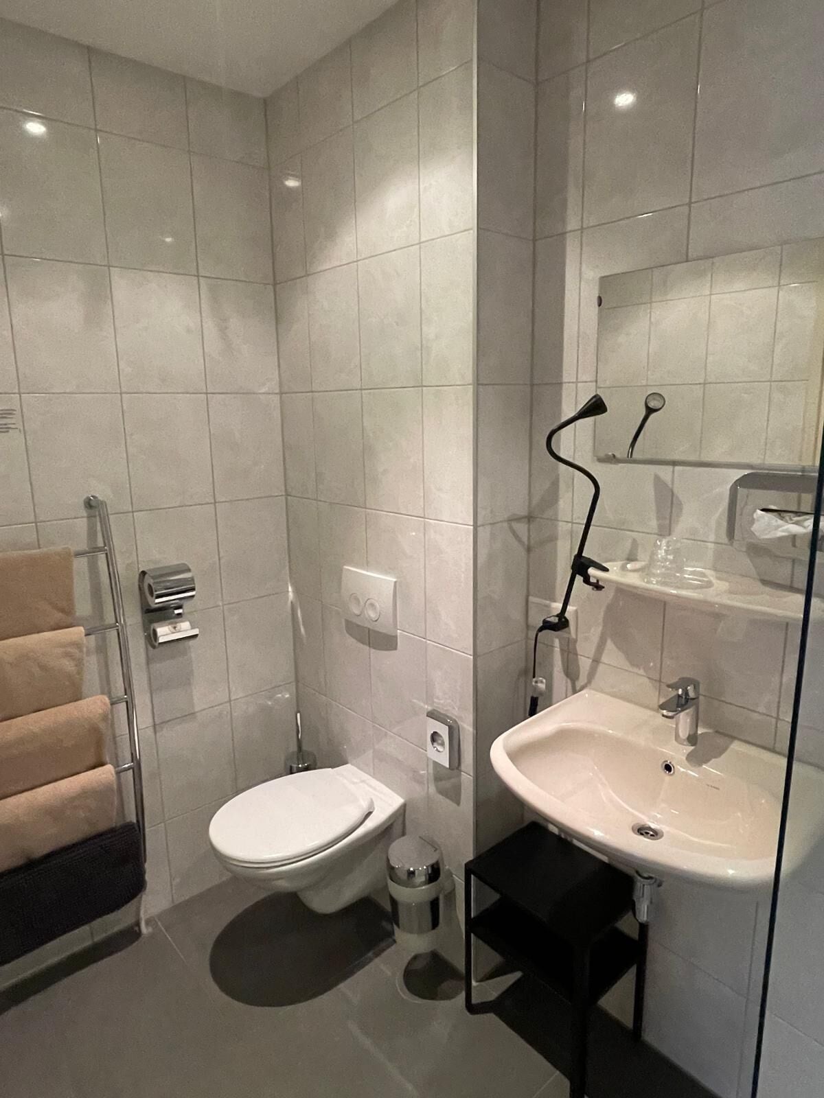 Une salle de bain moderne équipée de toilettes, d’un lavabo et d’une douche à parois en verre.