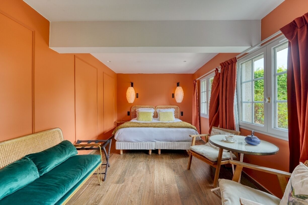 Un dormitorio con cama, sofá, mesa y ventana con cortinas.