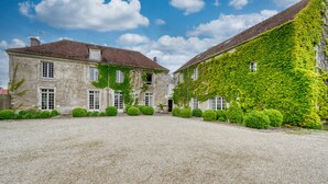 A historic stone building with ivy-covered walls, a gravel courtyard, and a red-tiled roof. - Domaine de Bellevue - Restaurant & Spa (Neufmoutiers-en-Brie)