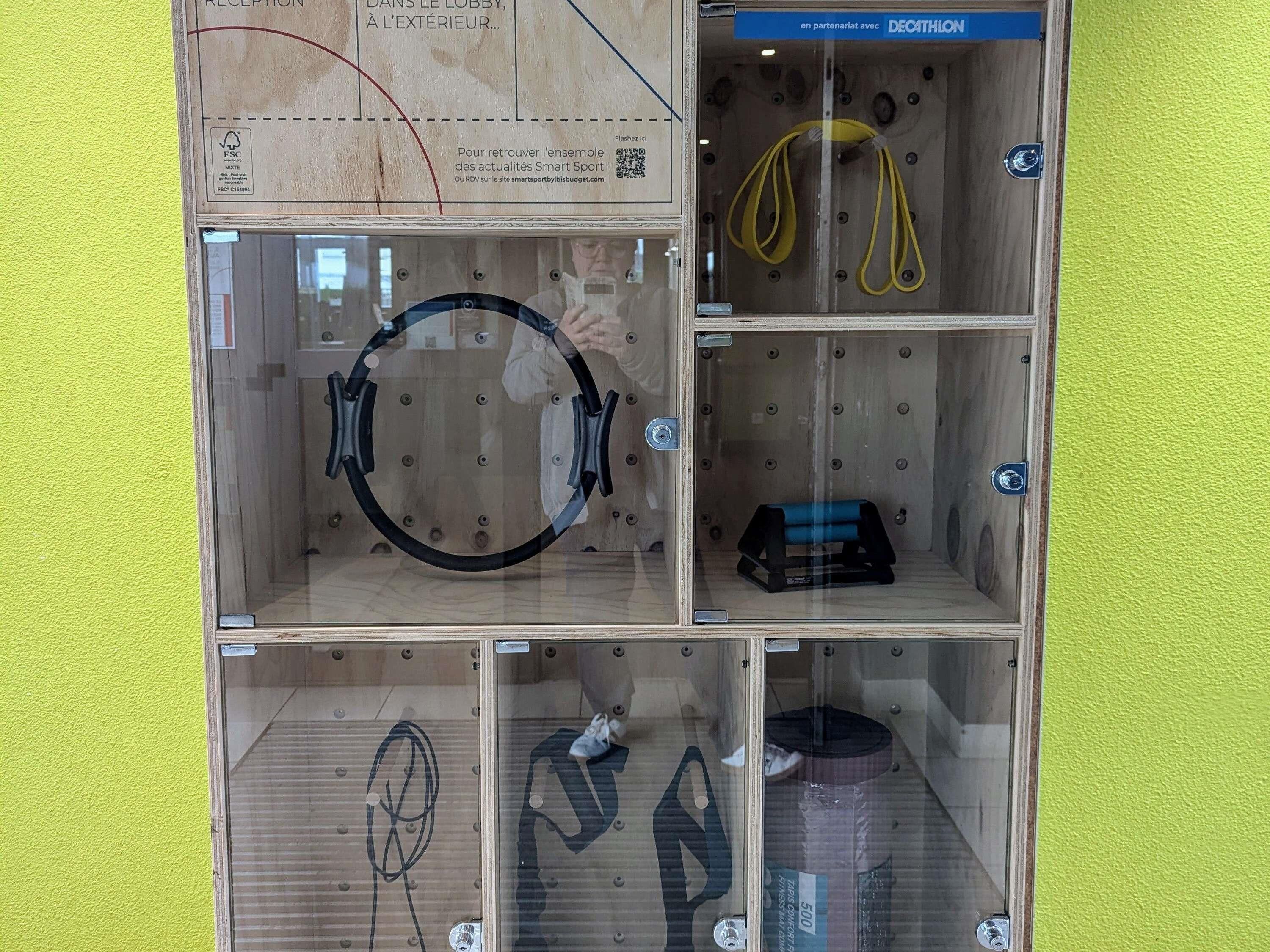 A reception area with a wooden interior, a glass partition, and various items including a yellow rope, a blue object, and a black item on the floor.