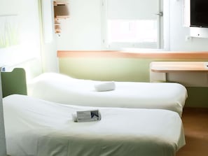 A hotel room with two beds, a small table, a window, and a television. - ibis budget Saint-Omer Centre (Saint-Omer)