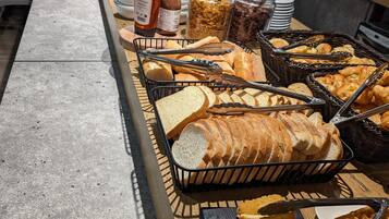 Un bufé con panes, pasteles y acompañamientos varios.