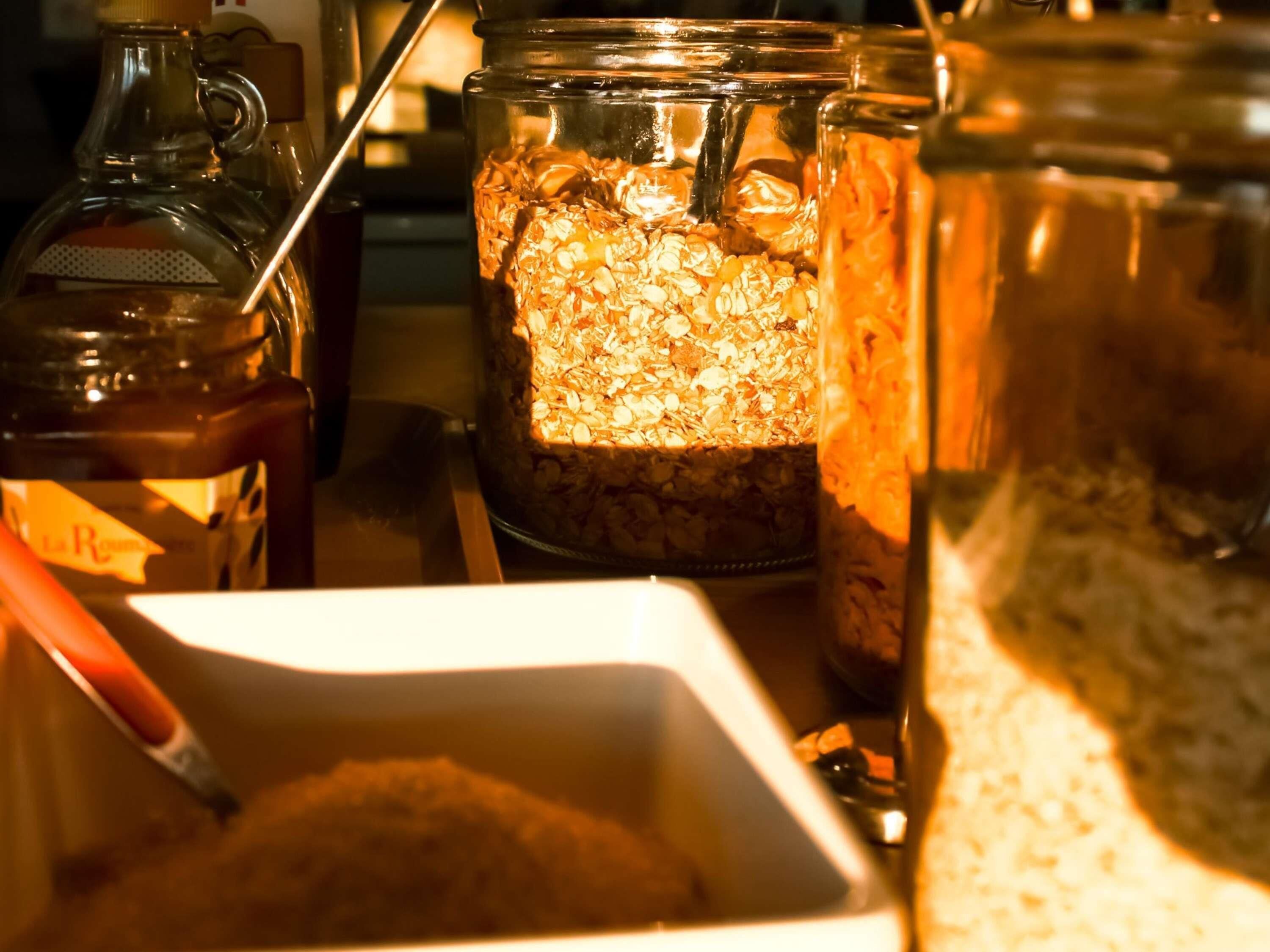 A kitchen with a coffee maker, a jar of oats, and a container of sugar.