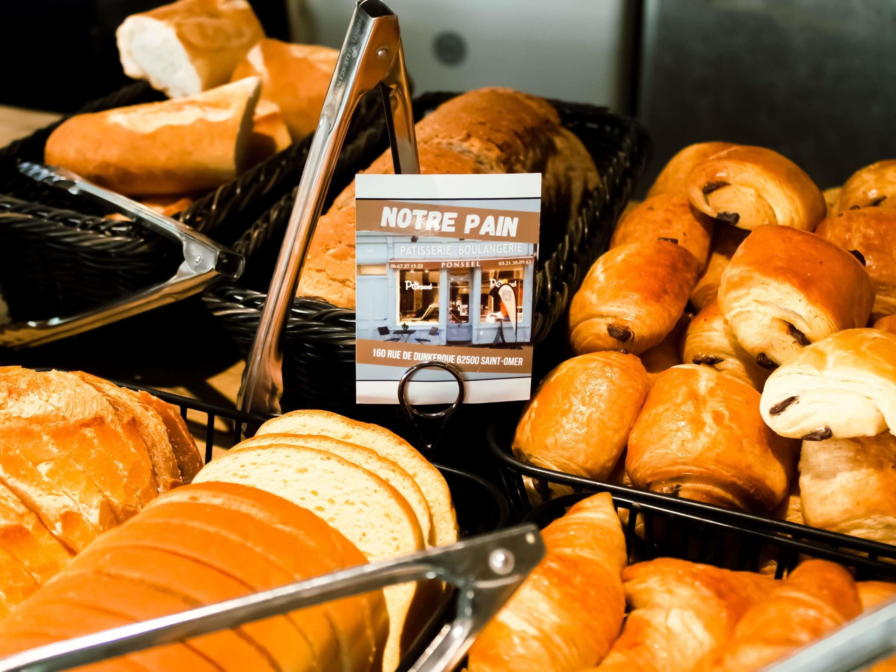 A variety of baked goods including bread and pastries, with a sign indicating 'NOTRE PAN' bakery.