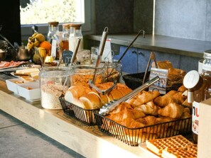 Un buffet de petit-déjeuner proposant une variété de pains, de viennoiseries et d’accompagnements.