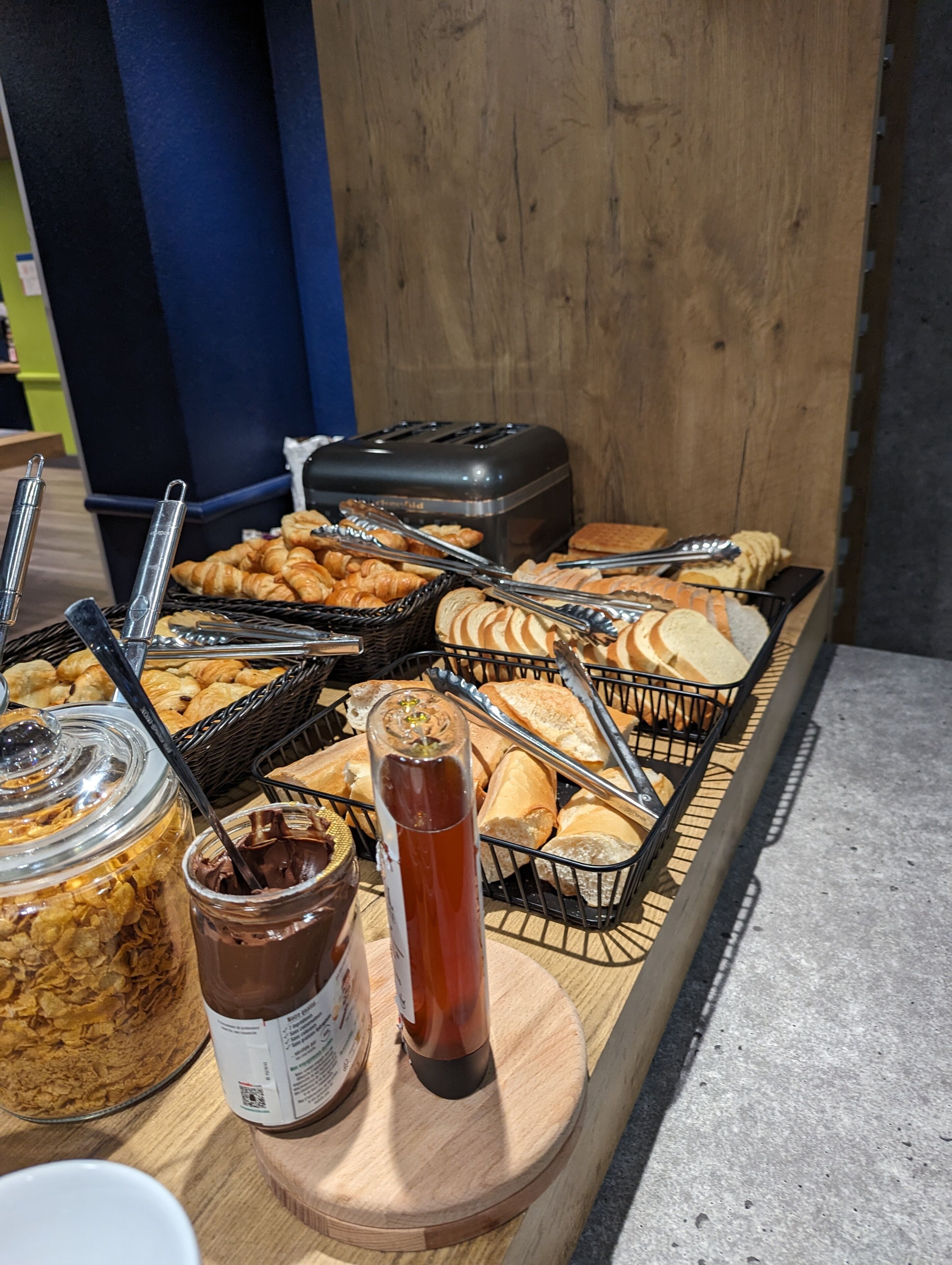 A buffet with various food items, including pastries, bread, and condiments.