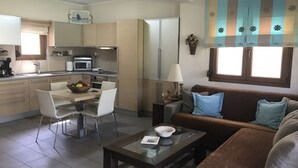 A compact living space with a kitchenette, dining area, and a sofa with cushions. - Luxury Maisonette in Halkidiki (Kassandra)