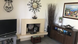 A living room with a fireplace, a television, and a wooden cabinet. - Luxury Maisonette in Halkidiki (Kassandra)