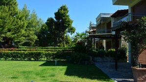 A hotel with a well-maintained garden, a clear sky, and a stone pathway leading to the entrance. - Luxury Maisonette in Halkidiki (Kassandra)