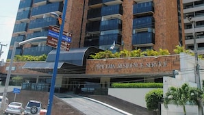 Edifício alto com várias varandas, placa indicando 'Iracema Residence Service' e céu claro.