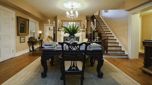 A dining area with a chandelier, a fireplace, and a staircase.