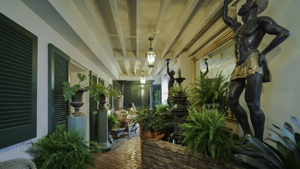 A hallway with a stone fountain, green plants, and a statue.