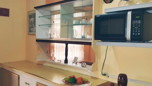 Una cocina con microondas, una vitrina de vidrio y un frutero sobre la encimera.