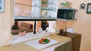 Una cocina con microondas, tostadora y un armario de vidrio con vajilla.