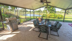 Une terrasse extérieure équipée d’un barbecue, d’une table, de chaises et offrant une vue sur un lac.
