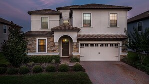 A two-story house with a garage, stone facade, and a well-maintained front yard.