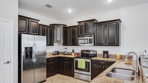 A modern kitchen with dark cabinetry, stainless steel appliances, and a granite countertop.