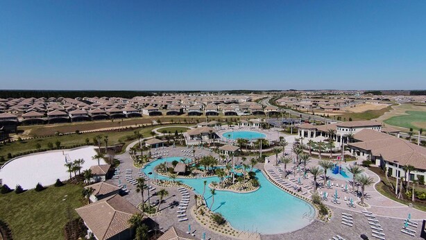 A resort with multiple swimming pools, sun loungers, and a golf course in the background.