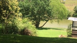 Eine grüne Fläche mit einem kleinen Teich, Bäumen und einem Gebäude mit einem geneigten Dach.