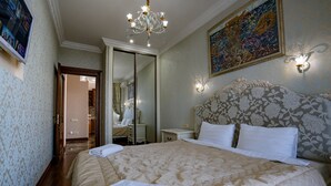 Ein Hotelzimmer mit einem großen Bett, einer Kristallleuchter, einem Spiegel und einem Gemälde an der Wand.