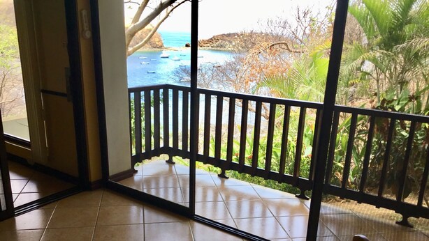 A room with a view of a coastal area, including boats on the water and a rocky shoreline.