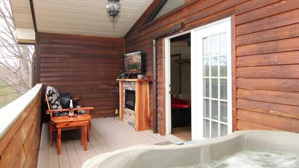 A wooden deck with a hot tub, a fireplace, and a dining area. - Gatlinburg Cabin, Free Tickets, Secluded Mtn Views, Hot Tub, Heart Tub, Internet (Gatlinburg)