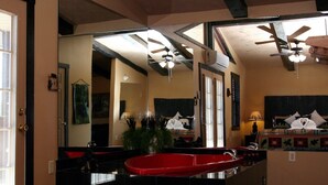 A bathroom with a large mirror, a red bathtub, a ceiling fan, and a bed with a decorative pillow arrangement. - Gatlinburg Cabin, Free Tickets, Secluded Mtn Views, Hot Tub, Heart Tub, Internet (Gatlinburg)