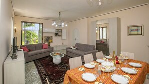 A spacious living area with two sofas, a dining table set for six, and a chandelier. - Villa Alberti Apt Emma 900m from Garda lake w/ shared Garden, Salò, Italy (Salò)