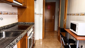 Cocina con encimeras de granito, pileta de acero inoxidable, horno y microondas.