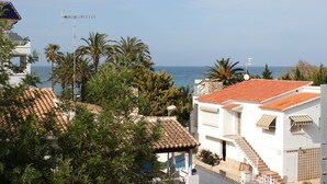 A coastal residential area with white buildings, red-tiled roofs, and palm trees. - 171 Medina Molins (Denia)