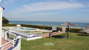 A pool area with a view of the ocean, a thatched umbrella, and a bench. - 171 Medina Molins (Denia)