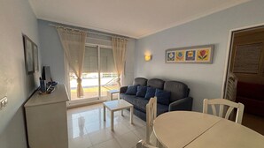 A living room with a sofa, a dining table, and a small kitchen area. - 171 Medina Molins (Denia)