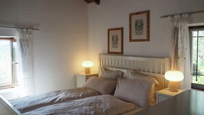 Un dormitorio con una cama, dos lámparas de noche y dos cuadros en la pared.