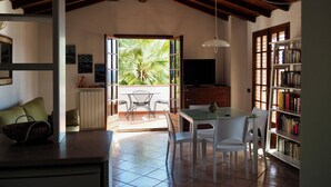 Amplia sala de estar con cocina, comedor y balcón con vista a palmeras.