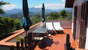 Una terraza con una mesa, sillas y dos tumbonas.