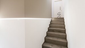 Una escalera de diseño minimalista que lleva a una puerta con el número 25.