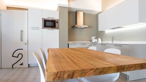 Una cocina moderna con armarios blancos, una mesa de comedor de madera y un microondas.