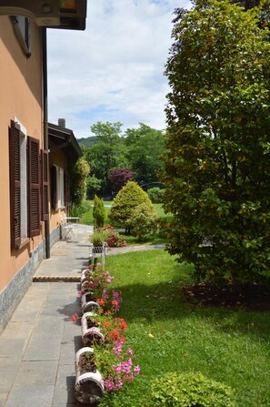A pathway lined with flower planters leading to a building with brown shutters.