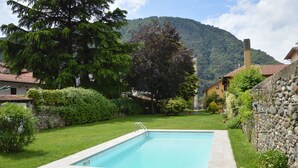 Ein rechteckiger Swimmingpool mit einer Steinmauer an einer Seite und einer Rasenfläche.