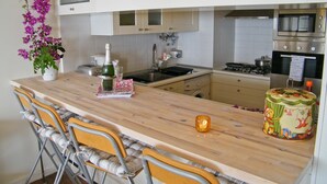 Une cuisine avec un îlot central en bois, des tabourets de bar, un four à micro-ondes et une cuisinière.
