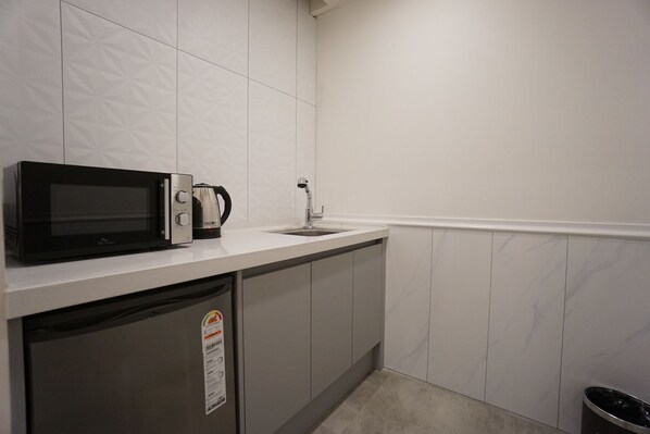 Cozinha compacta com micro-ondas, cafeteira e pia.